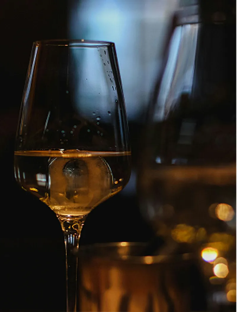 Calice di vino bianco illuminato durante una degustazione in sala