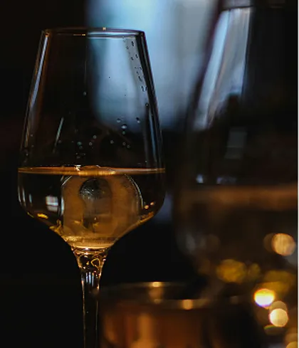 Calice di vino bianco illuminato durante una degustazione in sala