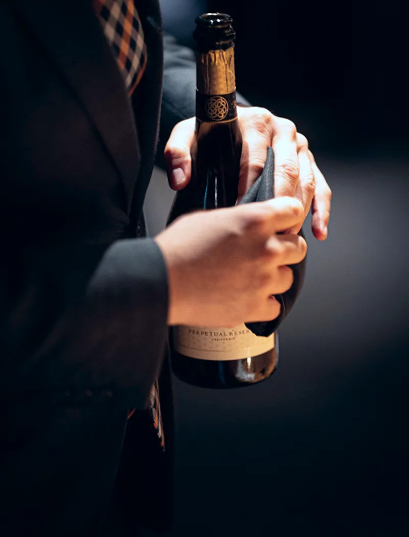 Un membro del personale di sala tiene in mano una bottiglia di vino