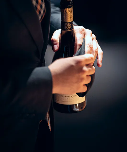 Un membro del personale di sala tiene in mano una bottiglia di vino